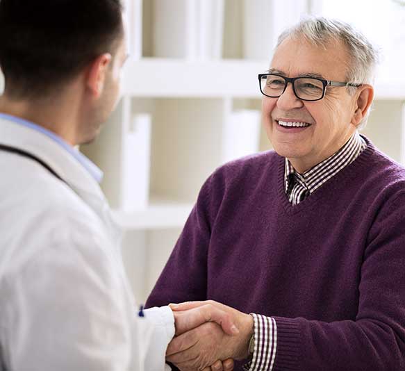Smiling happy healthy old male shaking with doctor