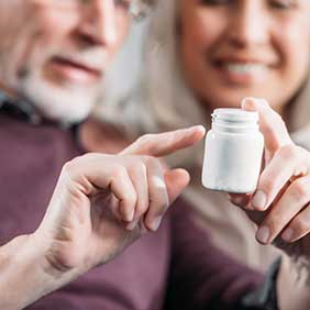 selective focus of senior man pointing at pill bottle in hand