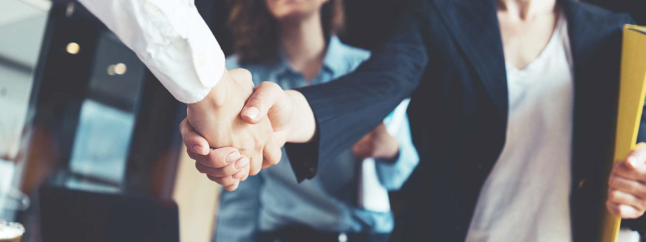 Young business people shaking hands in the office. Finishing successful meeting. Three persons. Wide screen panoramic